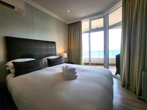 a bedroom with a large white bed with a large window at 603 Oyster Rock Umhlanga Rocks in Durban