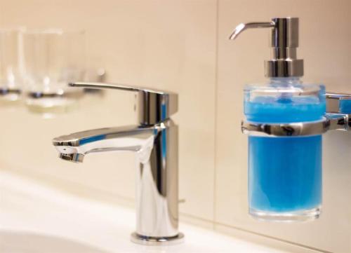 Una botella de cristal de jabón azul sentada en el lavabo del baño en Haus Gant en Sankt Gallenkirch