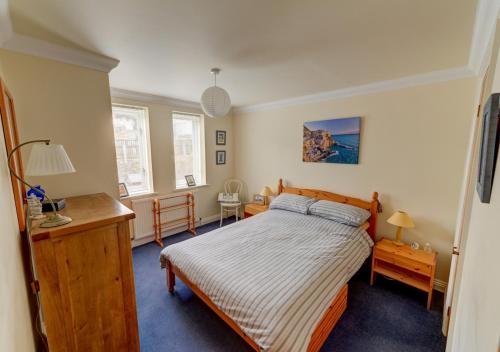 een slaapkamer met een bed, een bureau en 2 ramen bij Flat 3 Durlston Court in Swanage