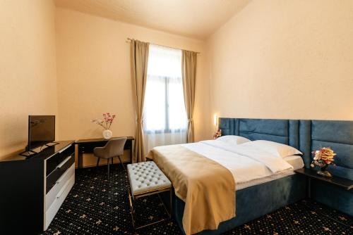 a bedroom with a bed and a desk and a window at Palace Bulevard Inn in Cluj-Napoca