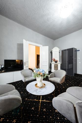 a living room with chairs and a table with a vase of flowers at Palace Bulevard Inn in Cluj-Napoca