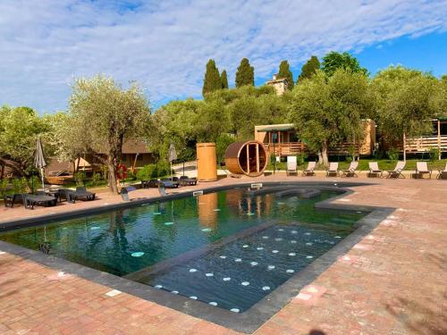 a swimming pool in a courtyard with chairs and trees at Campeggio della Colombaia in Padenghe sul Garda