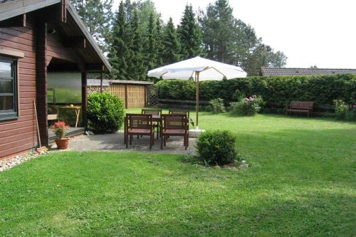 eine Terrasse mit einem Tisch und einem Sonnenschirm im Hof in der Unterkunft Holzhaus am Heidesee in Müden