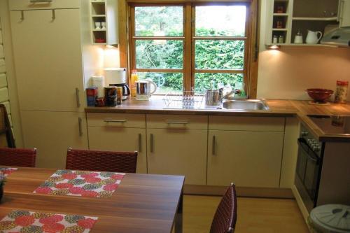 eine Küche mit einem Tisch und einem Fenster in der Unterkunft Holzhaus am Heidesee in Müden