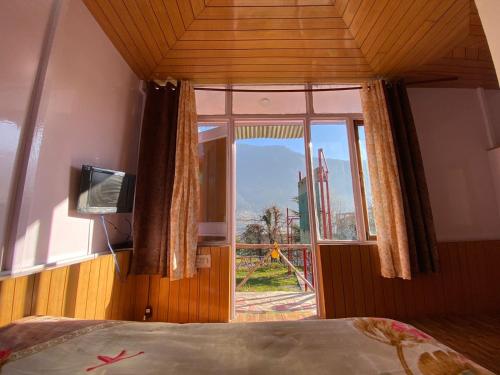 ein Schlafzimmer mit einem Bett und einem großen Fenster in der Unterkunft SAIRRA - Hotel & Restaurant in Manali