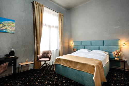 a bedroom with a bed and a chair and a window at Palace Bulevard Inn in Cluj-Napoca