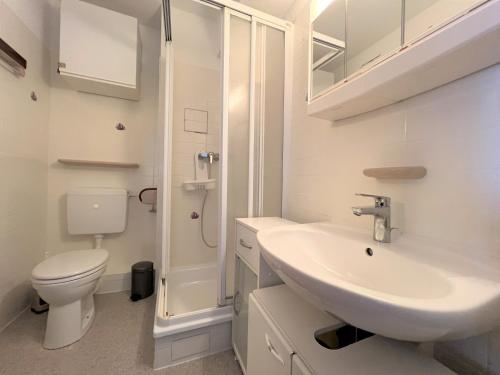 La salle de bains blanche est pourvue d'un lavabo et de toilettes. dans l'établissement Ferienpark Sierksdorf App 775 - Strandlage, à Sierksdorf