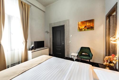 a bedroom with a bed and a green chair at Palace Bulevard Inn in Cluj-Napoca