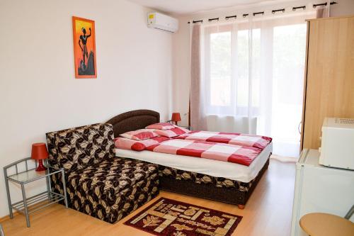 a small bedroom with a bed and a chair at SovaApartman in Hajdúszoboszló