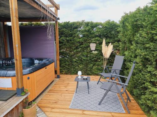 eine Terrasse mit einem Whirlpool und einem Stuhl auf einer Terrasse in der Unterkunft LE COTTAGE BARBIZONNAIS avec jacuzzi privé à partir de 10 ans in Barbizon