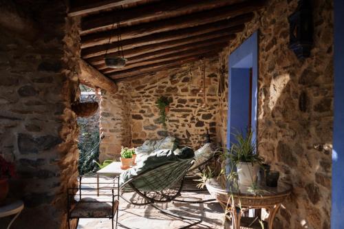 a patio with a table and chairs and a stone wall at CASA RURAL La Moranta in Herguijuela