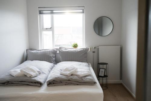 a white bed with two pillows and a mirror at Guesthouse Helluland in Þingeyjarsveit