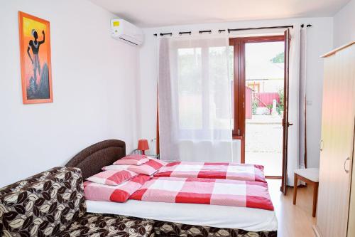 a bedroom with a bed with a red and white blanket at SovaApartman in Hajdúszoboszló