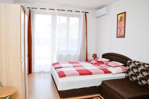 a bedroom with a bed and a large window at SovaApartman in Hajdúszoboszló