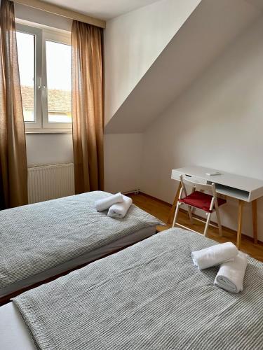 two beds in a room with a desk and a table at Karla’s House in Dobje pri Planini