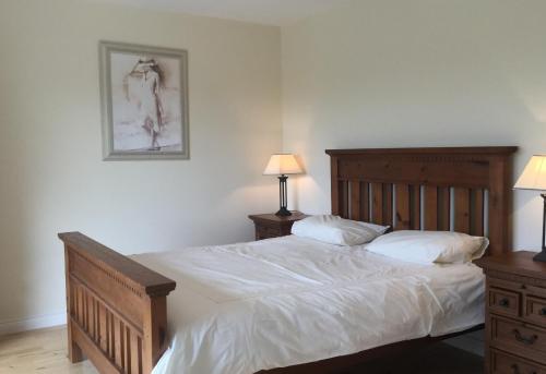 een slaapkamer met een bed met witte lakens en 2 lampen bij 3 bedroom home 15 mins drive from Kenmare town 