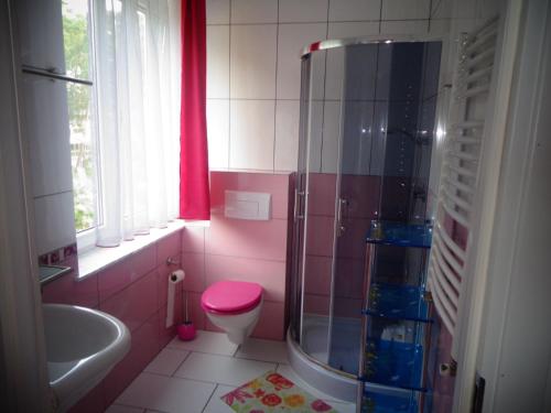 a pink bathroom with a toilet and a shower at Dom Sandi Dziwnowek in Dziwnówek