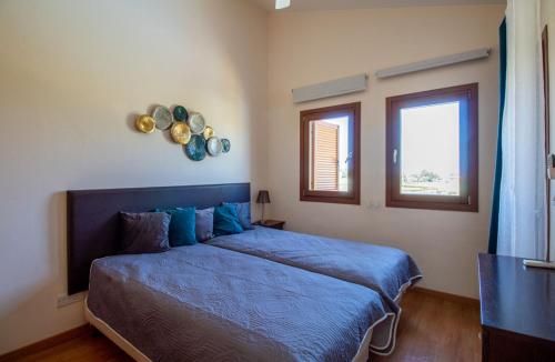 una camera con un letto blu e due finestre di Golf Villa in Aphrodite Hills HG07 a Kouklia