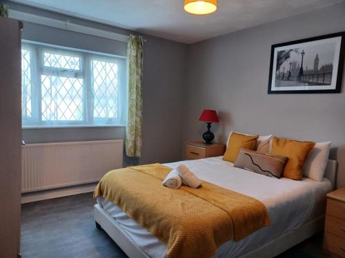 a bedroom with a large bed with an orange blanket at Melo House Grove-Huku Kwetu Spacious - Luton & Dunstable -4 Bedroom-L&D Hospital - Suitable & Affordable Group Accommodation - Business Travellers in Houghton Regis