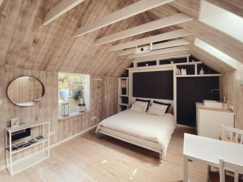 1 dormitorio con paredes de madera, 1 cama y 1 mesa en La Bulle d'EMBRUNS d'HERBE en Plogoff