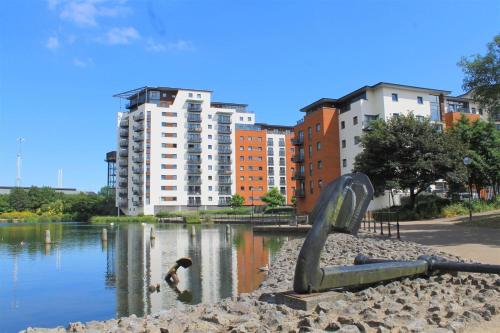 une sculpture d'un toboggan dans l'eau avec des bâtiments dans l'établissement Lush Cardiff Bay Apartment with Secure Parking and Fast Wifi, à Cardiff