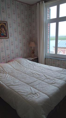 een slaapkamer met een groot wit bed met een raam bij chez margaut in Saint-Valery-sur-Somme