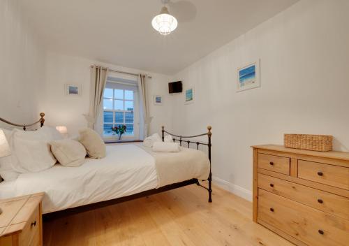1 dormitorio con 1 cama, vestidor y ventana en Cutter Cottage, en Swanage