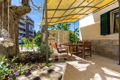 un patio con mesa y sillas bajo una sombrilla amarilla en Apartments Casa Saina, en Rovinj