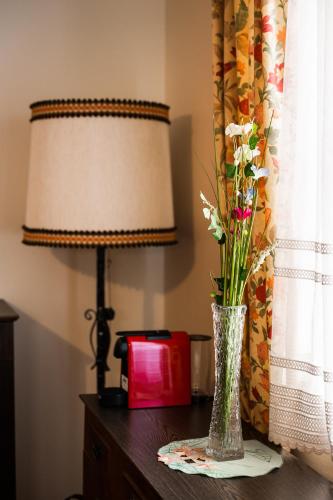 a vase with flowers on a table next to a lamp at PANORAMA SportHOTEL in Wenigzell