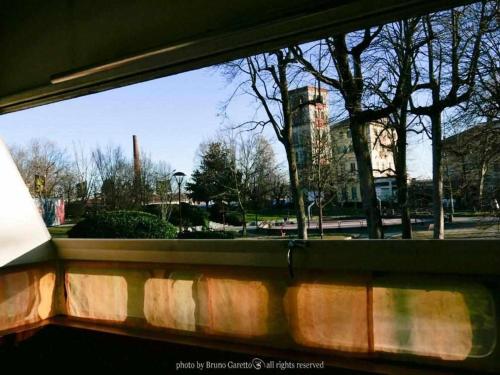 a window with a view of a street and trees at La Serra Olivetti in Ivrea