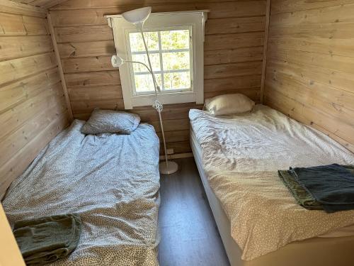 two beds in a wooden room with a window at House in Akersberga Stockholm Beach and Sea in Åkersberga