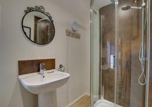 a bathroom with a sink and a shower with a mirror at SandyCastle in Swanage