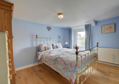 a bedroom with a bed with blue walls and a window at Little Steppes in Swanage