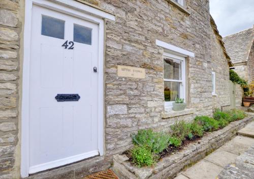 a white door on the side of a stone house at Little Steppes in Swanage
