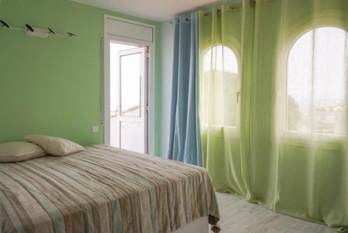 1 dormitorio con 1 cama con paredes y ventanas verdes en Apartment Platja de Aro con piscina y vistas al mar, en Platja d'Aro