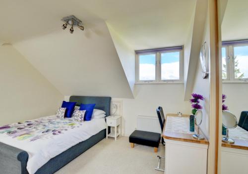 a bedroom with a bed with blue pillows and a desk at 3 The Downs in Swanage