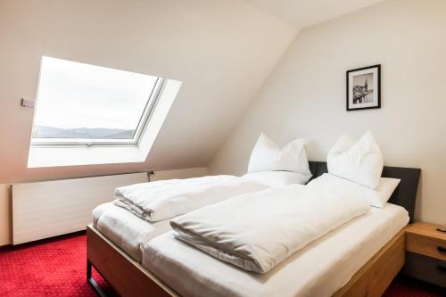 a bedroom with two beds with white pillows and a window at PANORAMA SportHOTEL in Wenigzell