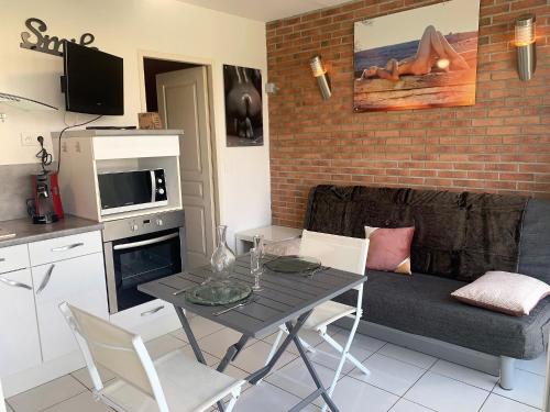 une cuisine et un salon avec une table et un canapé dans l'établissement Appartement Village Naturiste Macadamia, au Cap d'Agde