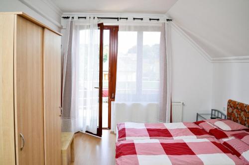 a bedroom with a red and white bed and a window at SovaApartman in Hajdúszoboszló