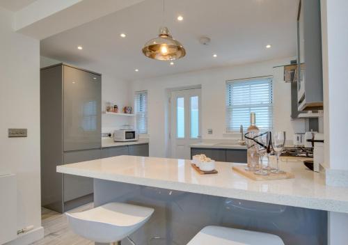 una cucina con un grande bancone bianco con due sgabelli di Marina View Townhouse a Weymouth