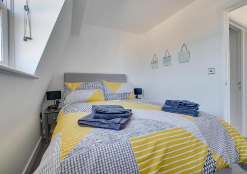 una camera da letto con un letto giallo e grigio con asciugamani di Marina View Townhouse a Weymouth