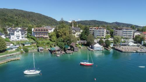 two boats are docked in the water in a town at Villa Auguste in Pörtschach am Wörthersee