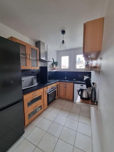 une cuisine avec des armoires en bois et un réfrigérateur noir dans l'établissement Appartement cosy proche du tram, à Montpellier