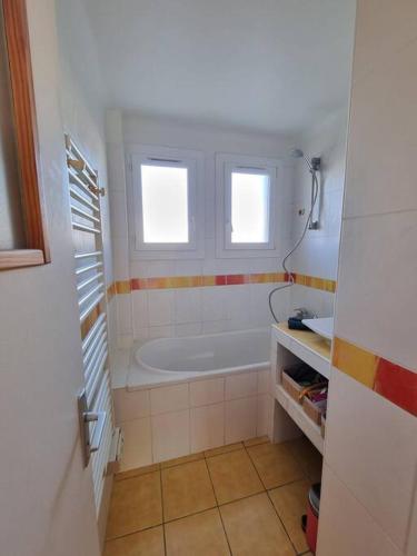 une salle de bain blanche avec une baignoire et un lavabo dans l'établissement Appartement cosy proche du tram, à Montpellier