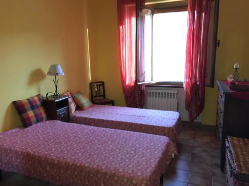een kamer met 2 bedden en een raam met rode gordijnen bij IL DOLCE ULIVO casa vacanze (up to 5 sleep) in Cascinette