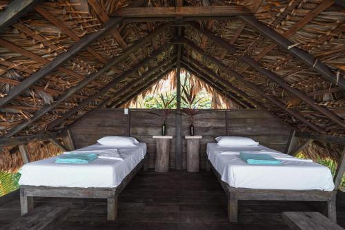 grupa czterech łóżek w drewnianym pokoju w obiekcie El Vijo Surf w mieście Nuquí