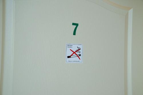 a white door with a sign on it with a no smoking sign at SovaApartman in Hajdúszoboszló
