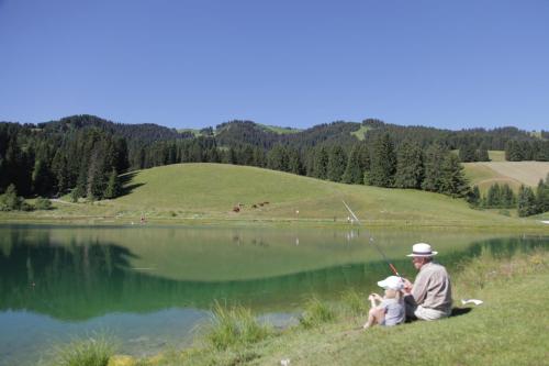 a man and two children sitting next to a lake at Mamie Meg&egrave;ve in Meg&egrave;ve