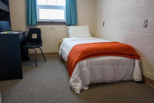 a bedroom with a bed and a desk and a window at Residence & Conference Centre - Timmins in Timmins