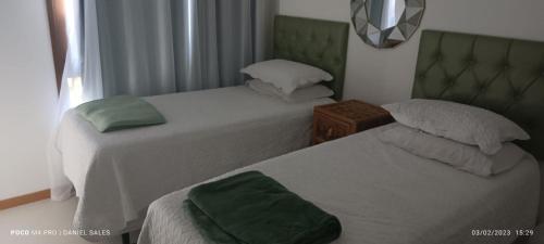 a bedroom with two beds and a green headboard at TAVARUA ITACIMIRIM d in Itacimirim